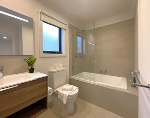 Une salle de bain moderne équipée de toilettes, d’un lavabo et d’une douche.