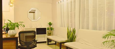 A modern living room with a sofa, a chair, a small table, and two potted plants.