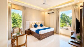 A modern hotel room with a large bed, a desk, a chair, and a TV. - Dwelling residency (Greater Noida)