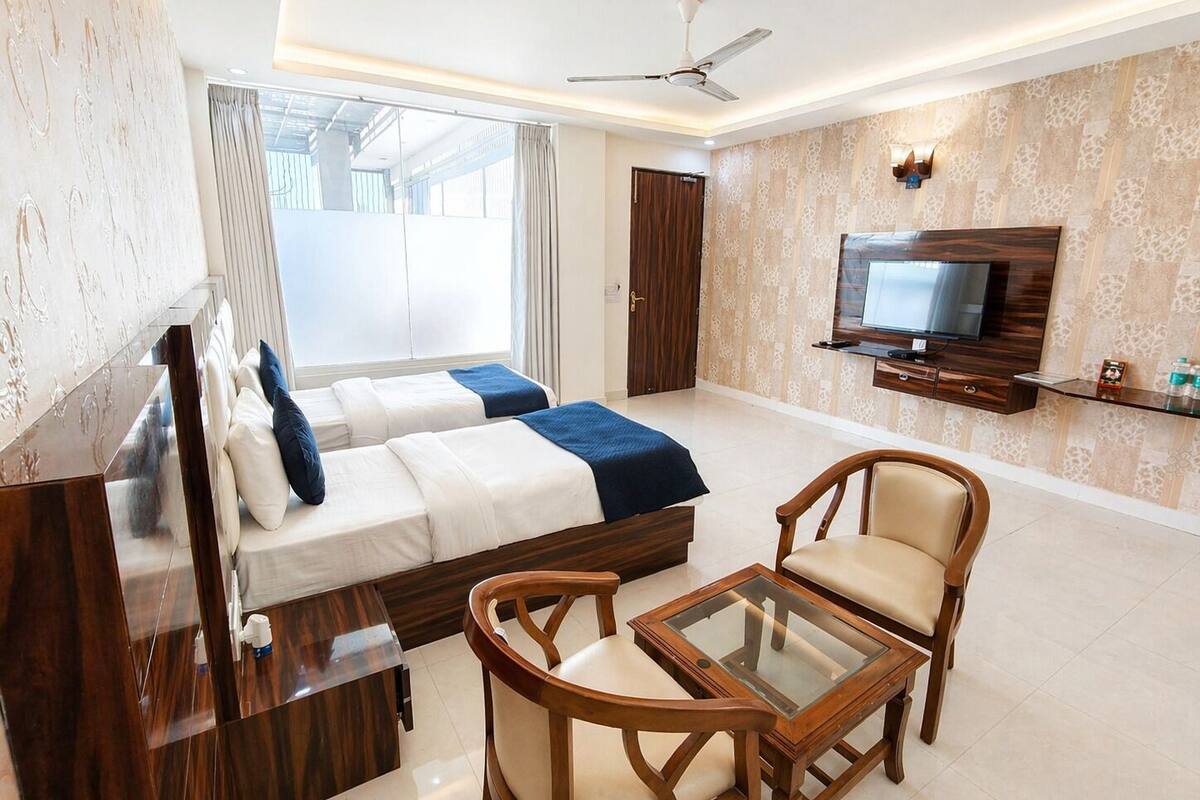 Une chambre d’hôtel avec deux lits, une télévision, un ventilateur de plafond, un bureau et un coin salon.