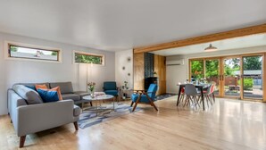 Un salón amplio con un sofá gris, sillones azules, una mesa de centro y un comedor con mesa y sillas.