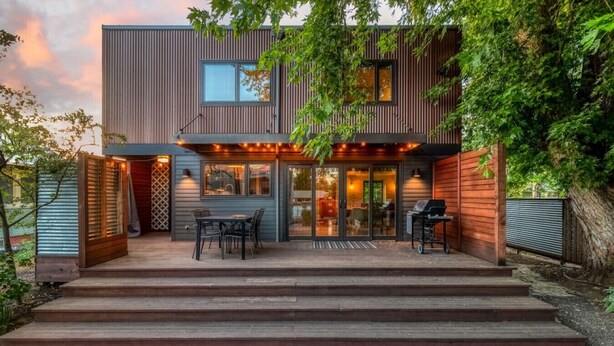 Una casa moderna de dos pisos con un porche cubierto, comedor y zona de barbacoa.