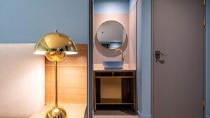 A bathroom with a round mirror, a blue sink, and a gold floor lamp. - WONJU Hotel Ippda (Wonju)