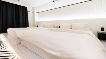 A modern hotel room with a large bed, a bedside table, a projector, and a blackout curtain.