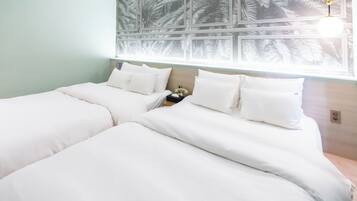 A double bed with white bedding, a nightstand with a lamp, and a wall with a leaf pattern.