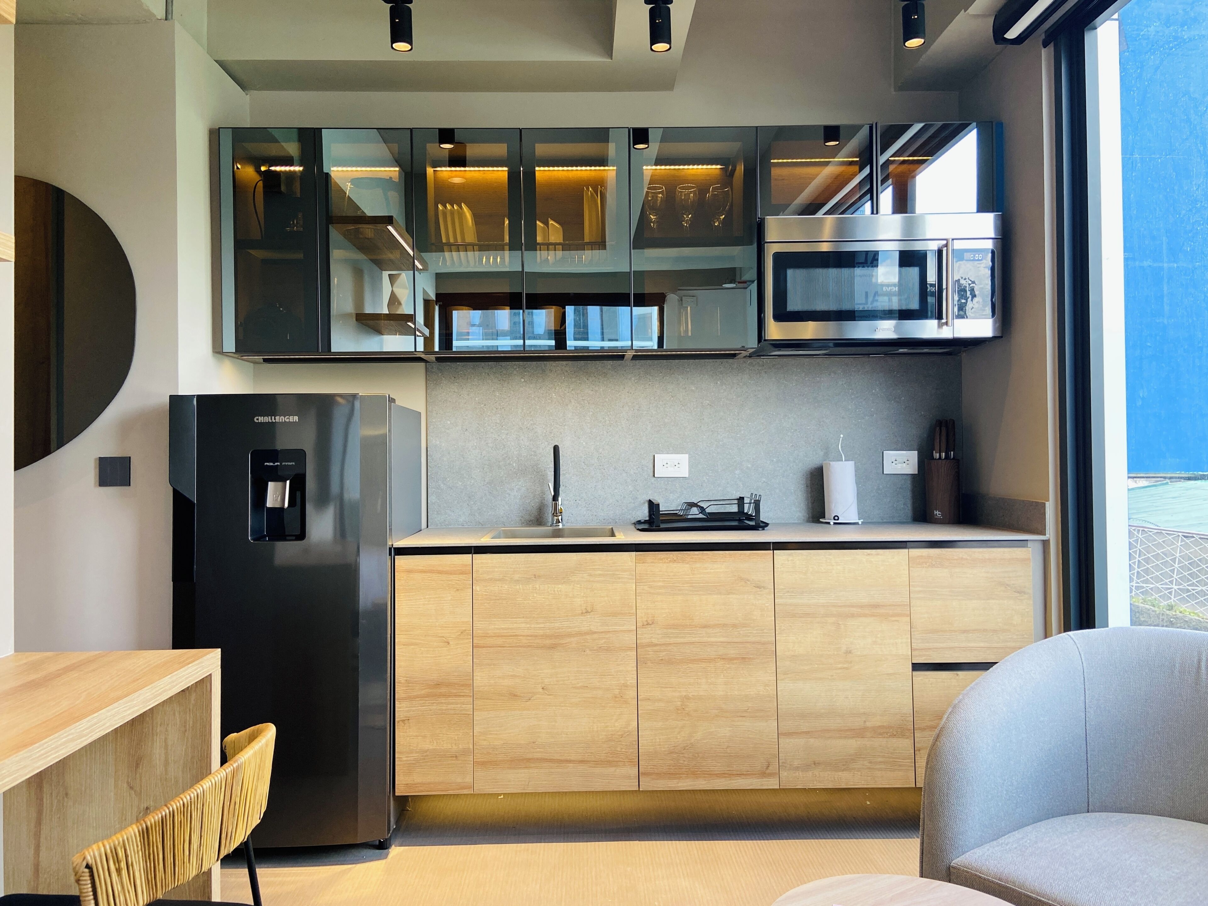 Una cocina moderna con refrigerador integrado, microondas y un comedor con encimera de vidrio.