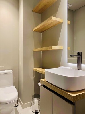 A modern bathroom with a white sink, wooden shelves, and a toilet. - Wynwood House 100 (Bogotá)