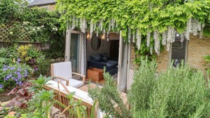 Un espace extérieur accueillant, aménagé avec une table et des chaises, et entouré d’une végétation luxuriante et de plantes en fleurs.