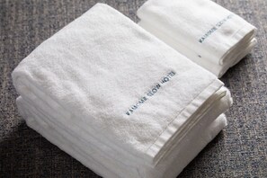 Toallas blancas dobladas con cuidado y texto bordado sobre una superficie texturizada.