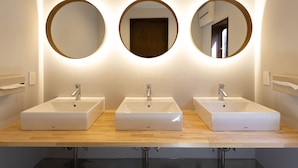 Un baño con tres lavabos, cada uno con un espejo encima.
