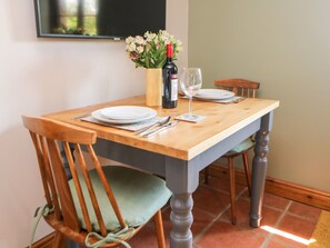 A dining table with two chairs, a wine bottle, and a glass. - Old Post Office Barn (Leek)