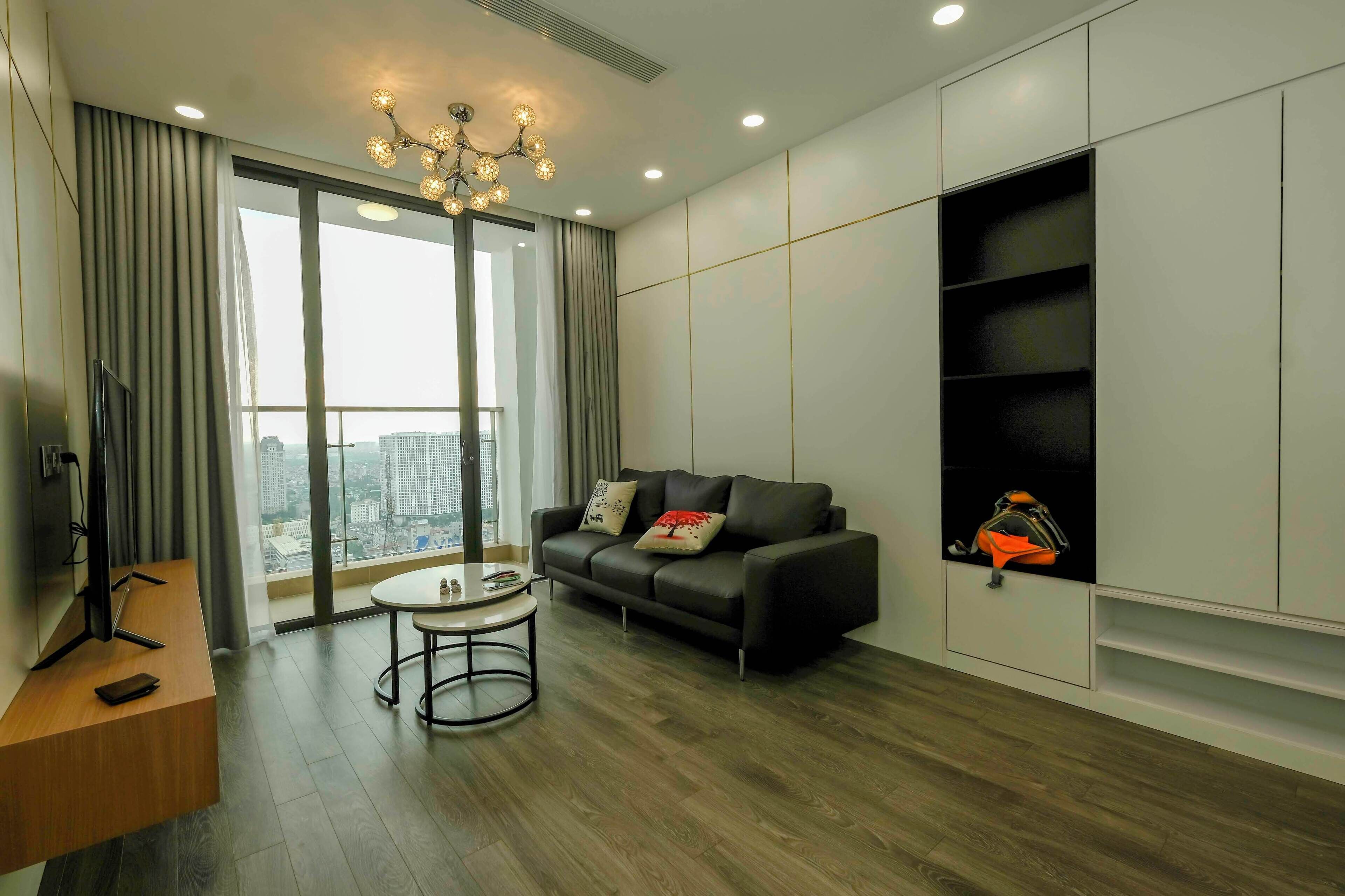 A modern living room with a sofa, a round coffee table, and a television on a wooden desk.