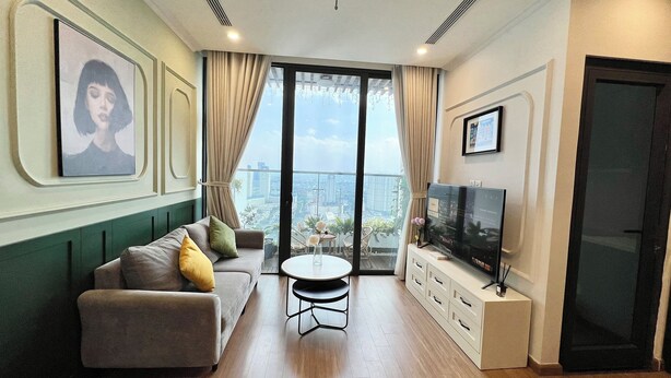 Ein modernes Wohnzimmer mit einer Couch, einem Couchtisch, einem Fernseher und einem Balkon mit Blick auf die Stadt.