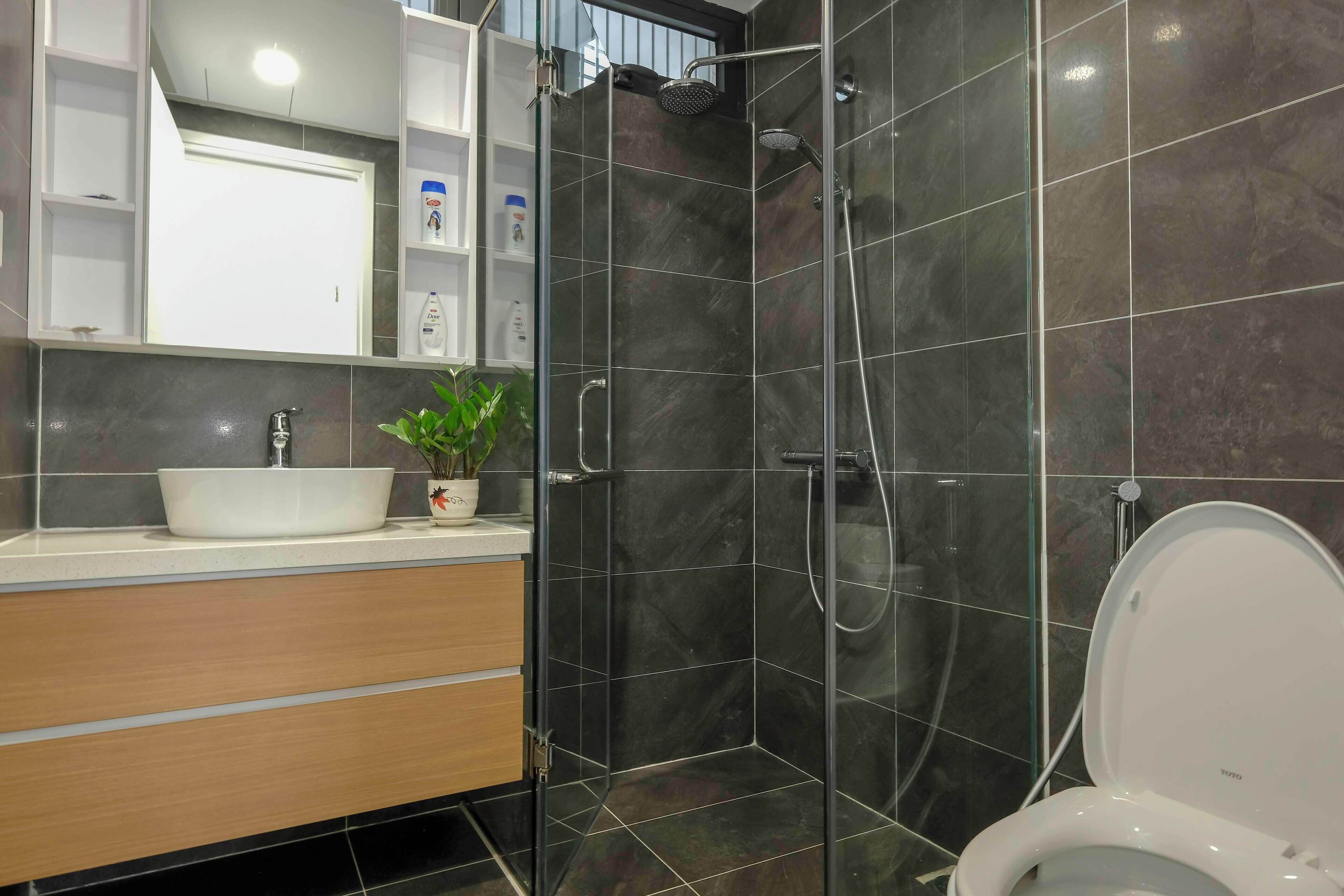 A modern bathroom with a glass-enclosed shower, a white sink, and a toilet.