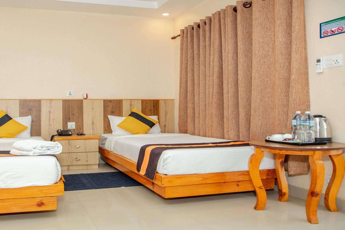 Ein Hotelzimmer mit zwei Betten, Holz-Kopfteilen und einem kleinen Holztisch mit Annehmlichkeiten.