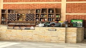 A brick wall with shelves of bottles and a Coca-Cola refrigerator. - MeroStay 259 KB Resort (Purano Jhangajholi)