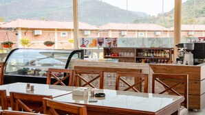A restaurant with outdoor seating, a counter with various beverages, and a mountainous backdrop. - MeroStay 259 KB Resort (Purano Jhangajholi)
