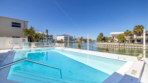 Una piscina con vistas a un puerto deportivo y edificios al fondo.