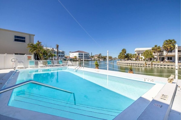 Una piscina con vistas a un puerto deportivo y edificios al fondo.