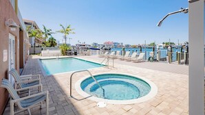A pool area with a hot tub, lounge chairs, and a view of the marina. - Clearwater Beach Waterfront Condo w/ Boat Slip (Clearwater)