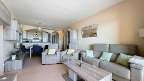 A modern living room with a sofa, coffee table, and dining area.