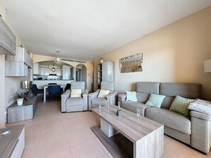 A modern living room with a sofa, coffee table, and dining area.