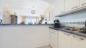 A modern kitchen with white cabinetry, a granite countertop, and a built-in dishwasher.