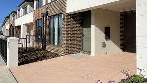 Un edifici residencial modern amb teulada plana, grans finestres i un camí pavimentat.