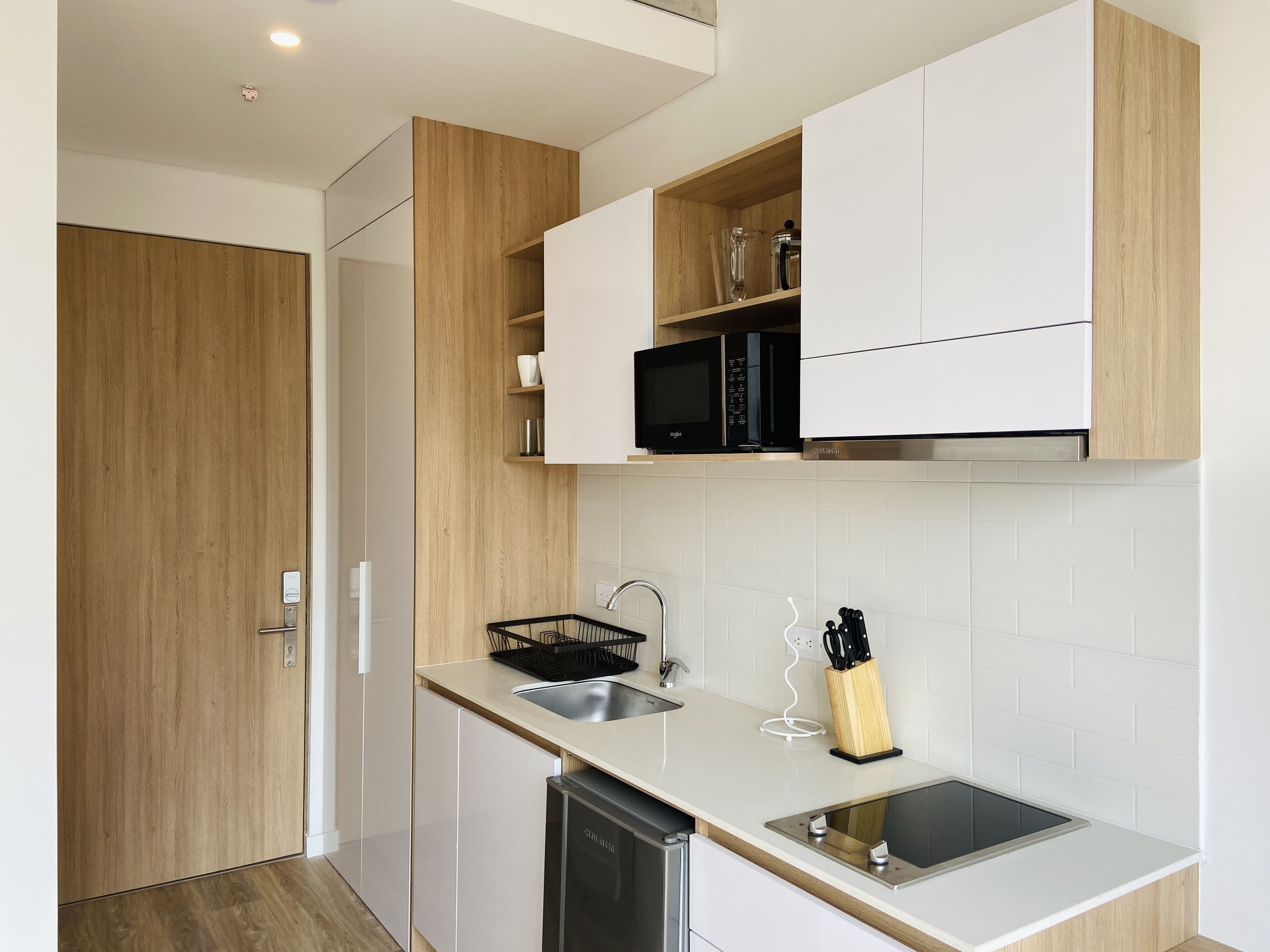 A modern kitchen with wooden cabinets, a microwave, a sink, and a dishwasher.