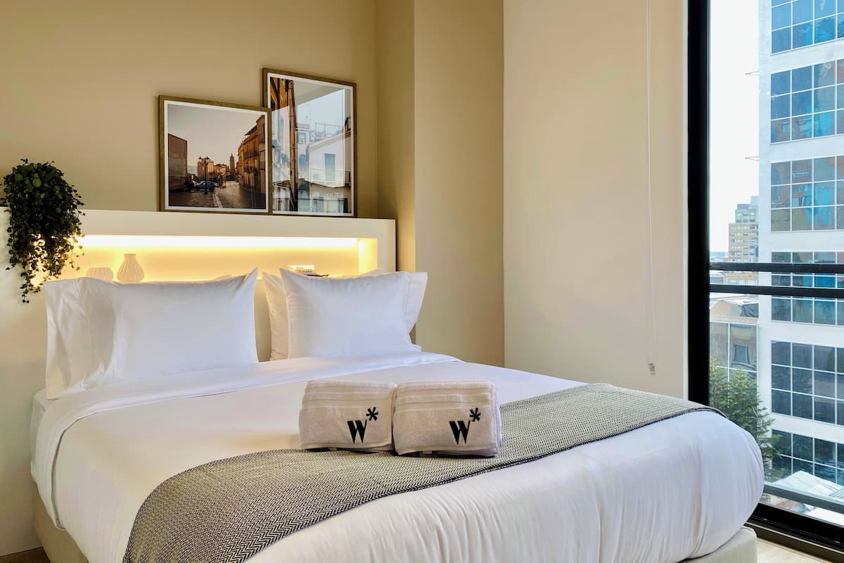 Ein Hotelzimmer mit Bett, großem Fenster und Blick auf die Stadt.