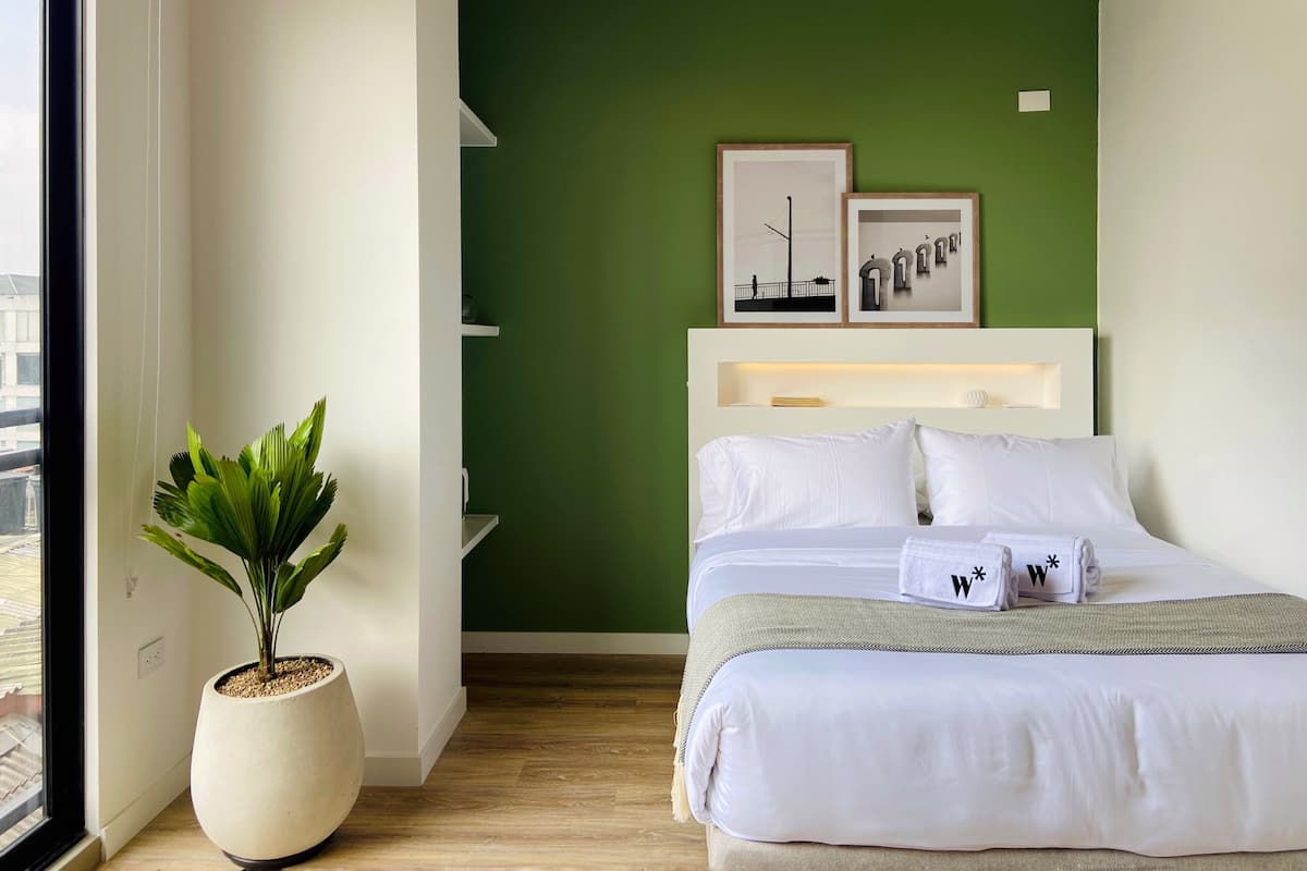 Ein Hotelzimmer mit einem Bett, einer Topfpflanze und Bildern an der Wand.
