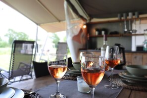 A table with wine glasses and a candle, set in a room with a view of the outdoors. - Safari Tent in Friesland near Nature (Twijzel)