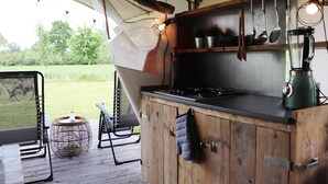 Une cuisine de taille réduite, équipée d’une cuisinière, d’ustensiles suspendus et d’une machine à café.