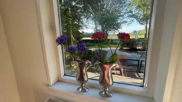 Två silvervaser med blommor står på en fönsterbräda.