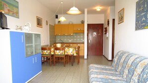 A compact living space with a kitchenette, dining area, and a sofa. - Apartment in Caorle (VE) (Caorle (VE))