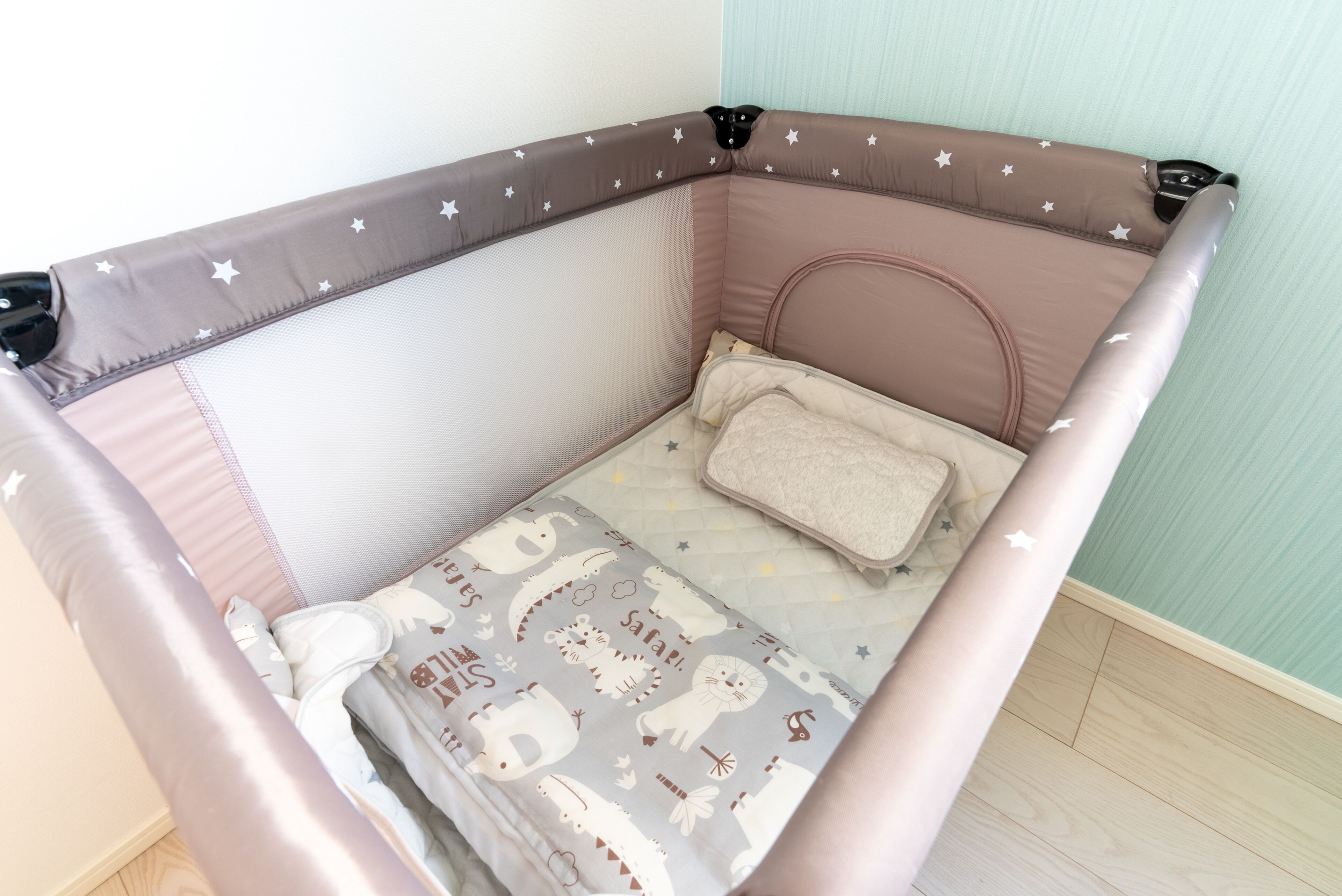 A baby crib with a star-patterned design, a padded mattress, and a blanket with animal prints.