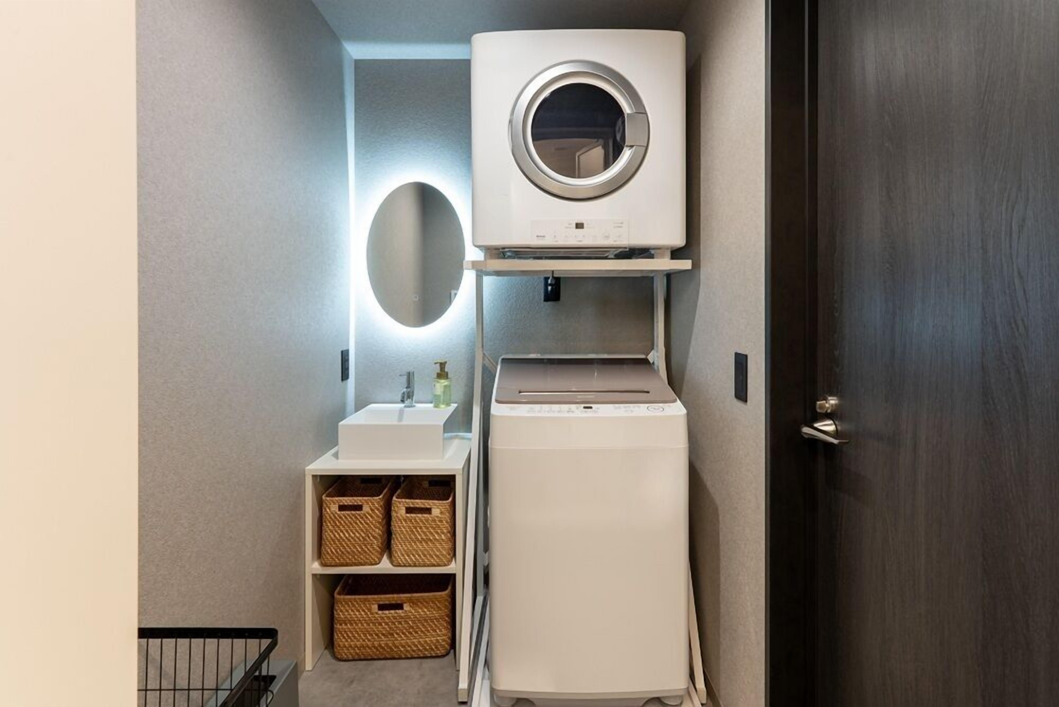A compact laundry room with a washing machine, dryer, and a small sink with baskets.