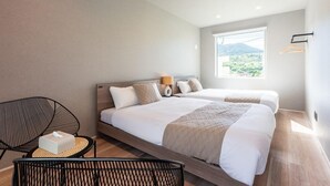 A modern hotel room with two beds, a sitting area with a chair, a small table, and a window with a view of greenery. - Grandioso Okinawa Pool Villa Kin 2 (Kin)