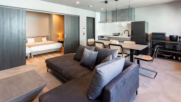A modern hotel room with a sofa, a dining table, a kitchen area, and a bed. - Grandioso Okinawa Pool Villa Kin 2 (Kin)