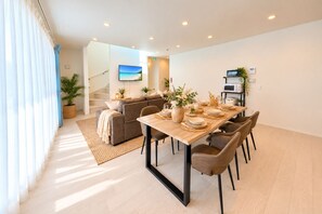 A modern living room with a dining area, a staircase, and a kitchen area. - Grandioso Okinawa Pool Villa Kin 2 (Kin)