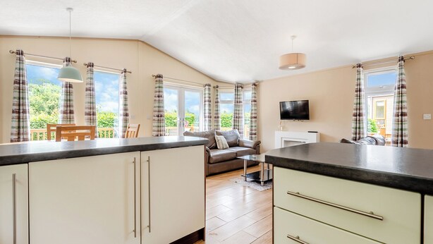 A modern kitchen with a dining area, a sofa, and a TV. - Stylish luxury lodge with meadow view. (Wattleborough, Nr Shrewsbury)