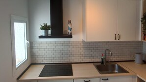 Uma cozinha moderna com armários brancos, painel de parede preto e uma janela.