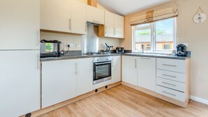 A modern kitchen with white cabinets, a built-in oven, a gas stove, and a window with a view.
