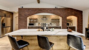 A modern kitchen with a large island, a brick backsplash, and skylights. - Harmony Ridge Ranch Nevada City (Nevada City)