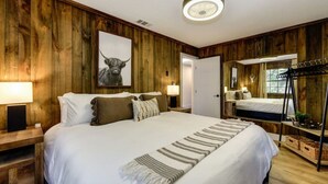A wooden-paneled bedroom with a large bed, bedside lamps, a mirror, and a ceiling fan. - Harmony Ridge Ranch Nevada City (Nevada City)