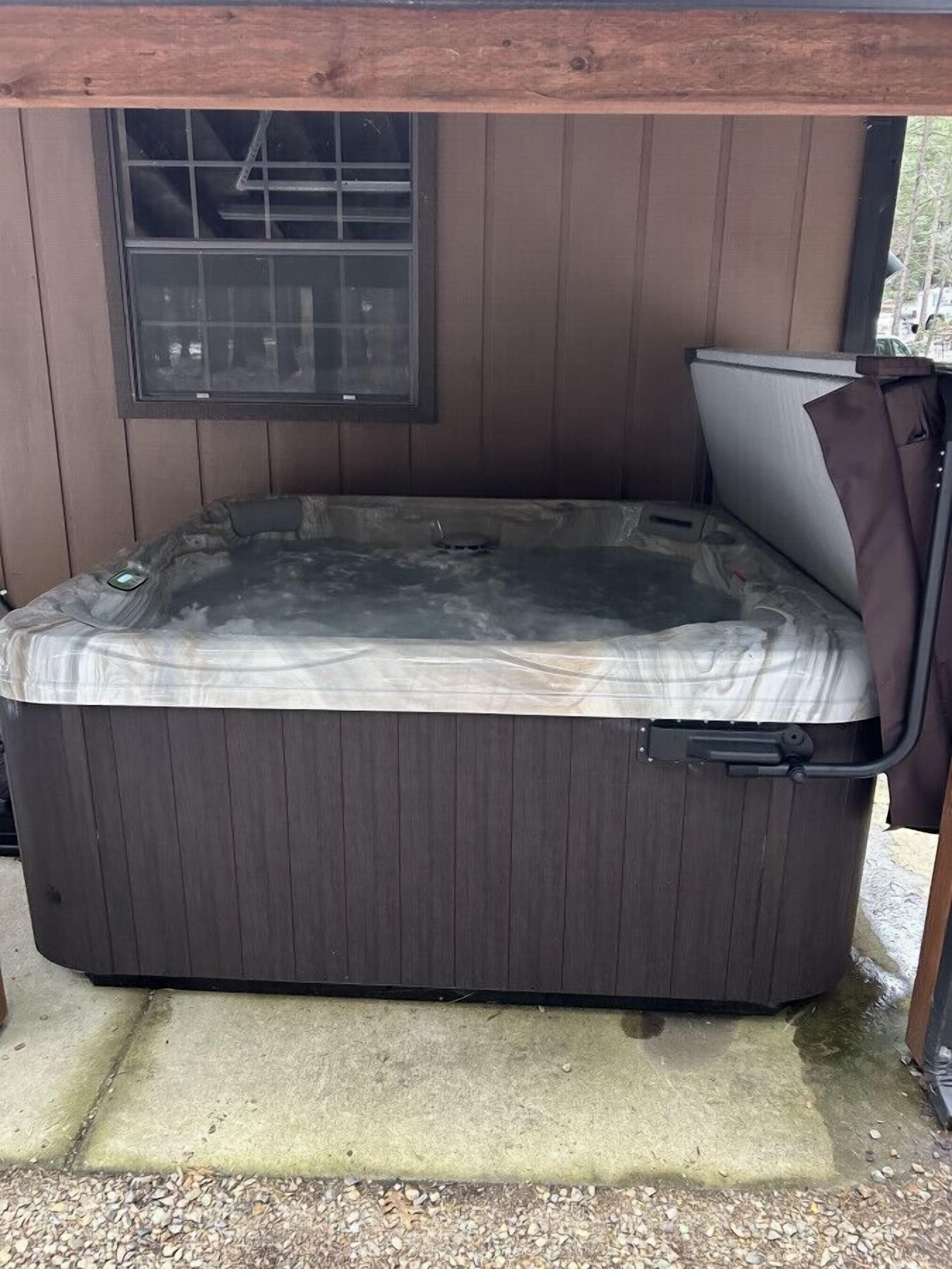 A hot tub under a wooden structure with a window above it.