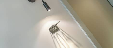 Una lámpara fijada al techo con el número '104' visible y una sombra proyectada en la pared.