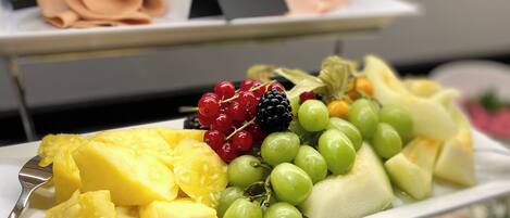 Eine Obstplatte mit Ananas, Trauben und Beeren auf einem weißen Teller.