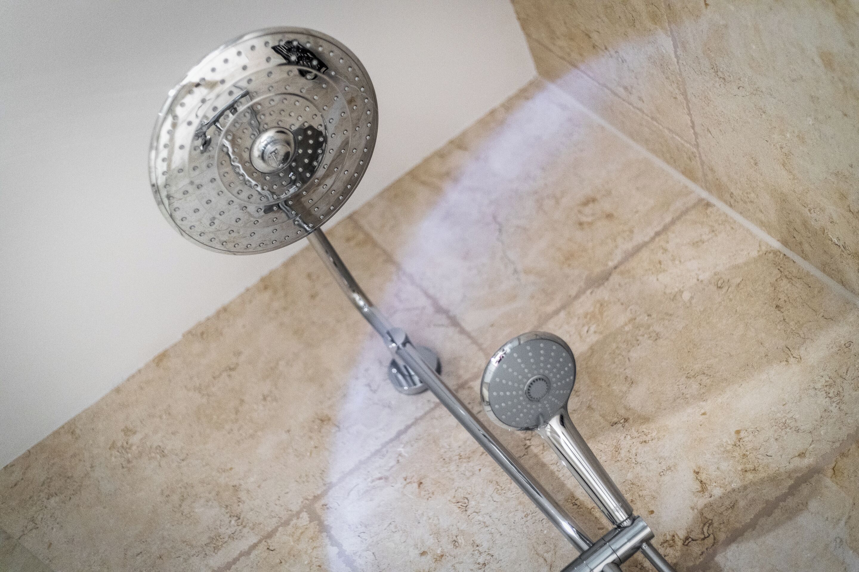 Een douche met een flexibele douchekop en een vaste douchekop bovenin.