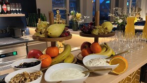 A breakfast buffet with various fruits, nuts, and a yogurt dish.